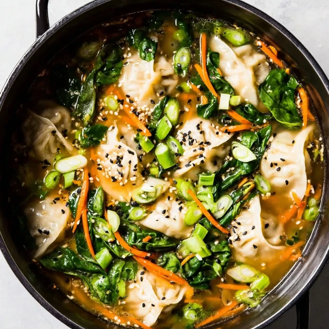 Homemade dumpling soup with tender dumplings, spinach, carrots, green onions, and sesame seeds in a savory broth
