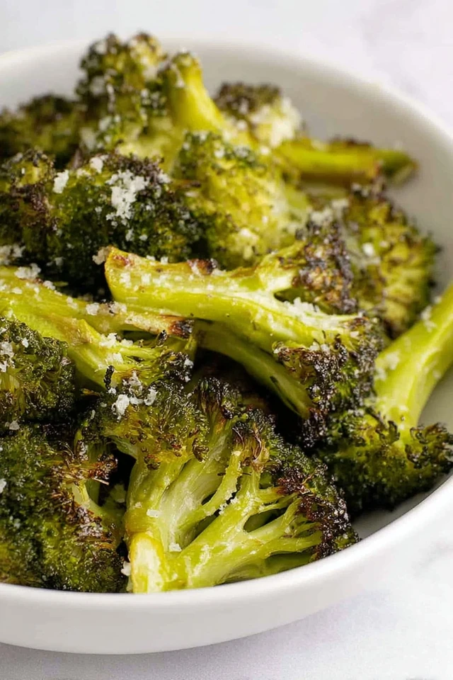 Crispy parmesan-roasted broccoli florets with golden edges served in a white bowl