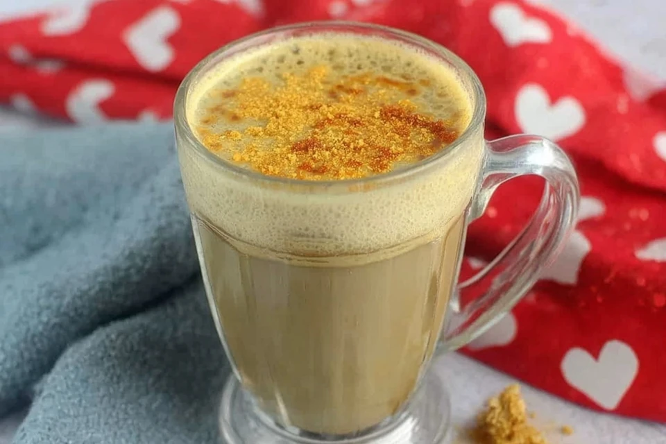Creamy banana milk coffee topped with light foam and warm spice in a glass mug