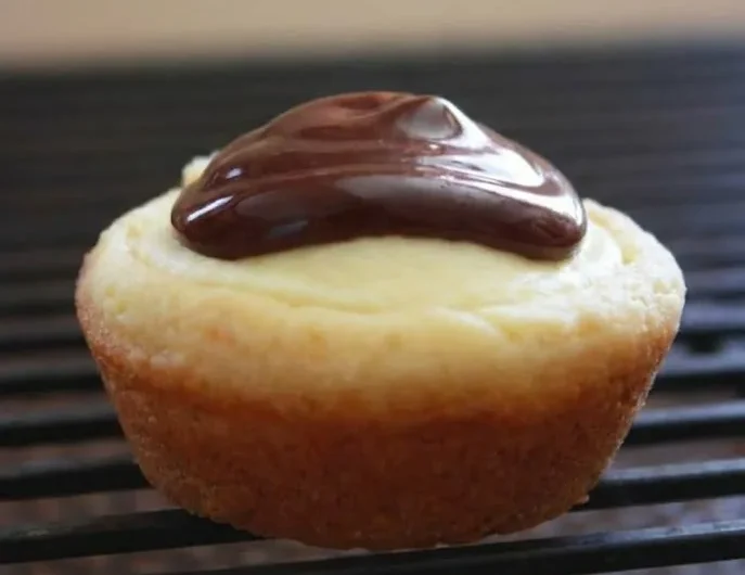 Boston cream pie cookies with vanilla cream and chocolate topping on a cooling rack