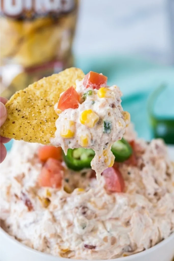 Tortilla chip scooping creamy Boat Dip Rotel Ranch Dip with corn, tomatoes, and jalapeños